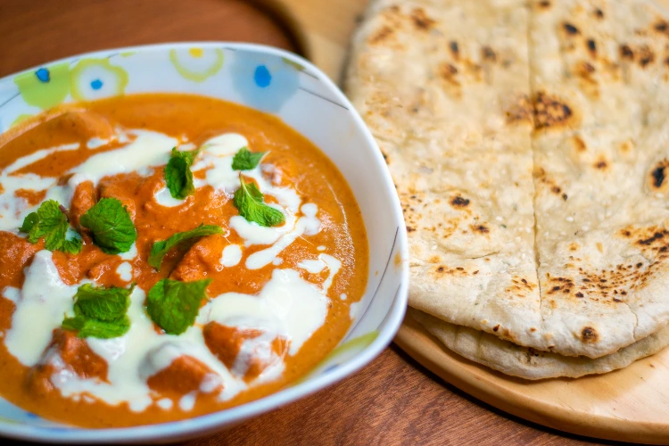 Chicken tikka masala with naan bread on a wooden board